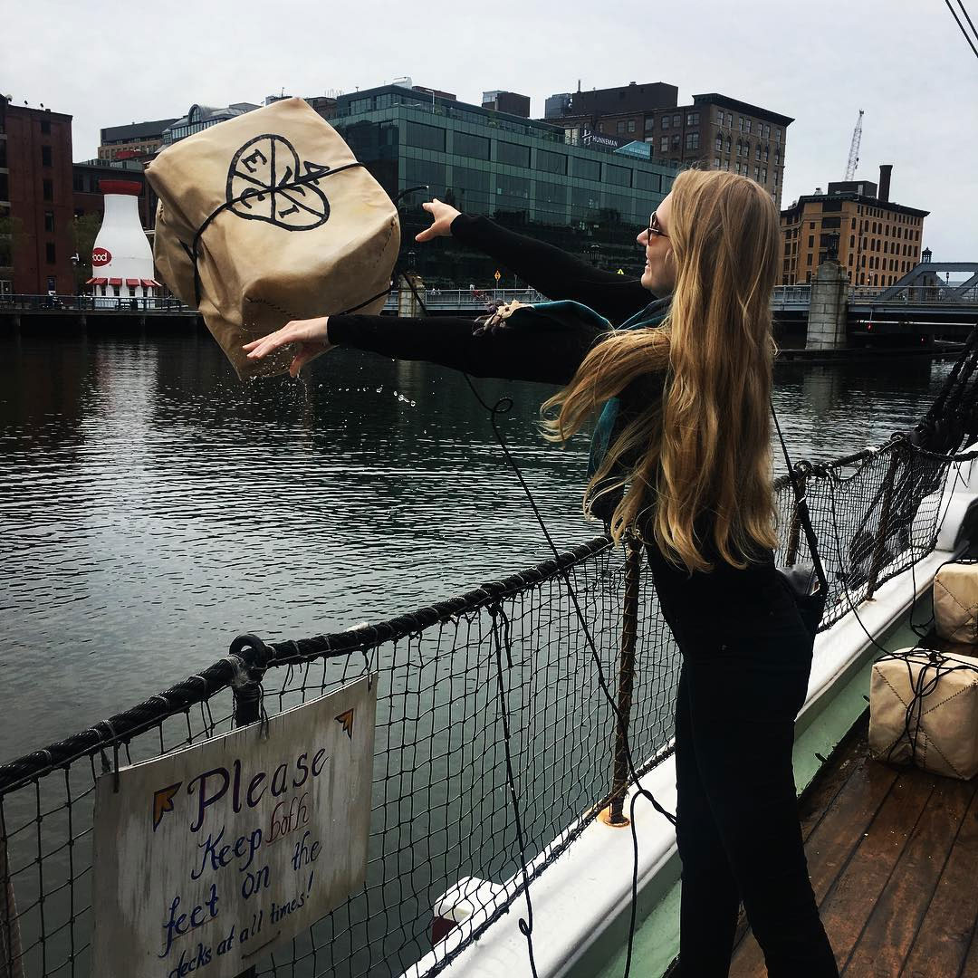 Jessica Kretzmann throwing a box of tea into Boston Harbour as part of an annual Boston Tea Party reenactment